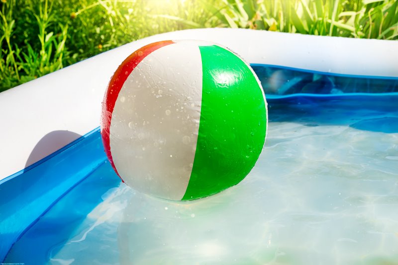 Ein Wasserball schwimmt auf der Wasseroberfläche eines Aufstellpools Ein Wasserball schwimmt auf der Wasseroberfläche eines Aufstellpools