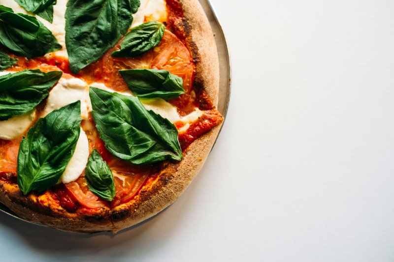 Fertige Pizza mit Basilikum auf einem Pizzastein