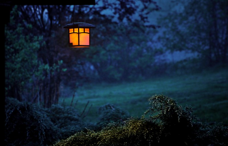 Gartenlampe hängt draußen in der Abenddämmerung Gartenlampe hängt draußen in der Abenddämmerung
