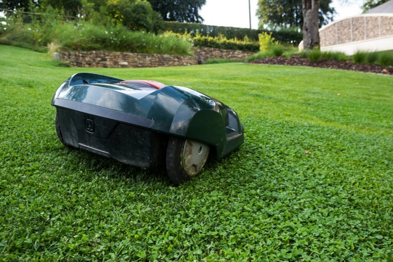 Ein Mähroboter verrichtet im Grünen seine Arbeit Ein Mähroboter verrichtet im Grünen seine Arbeit