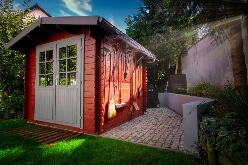 Ein rotes Holzhäuschen in einem Garten Ein Holzhäuschen in einem Garten