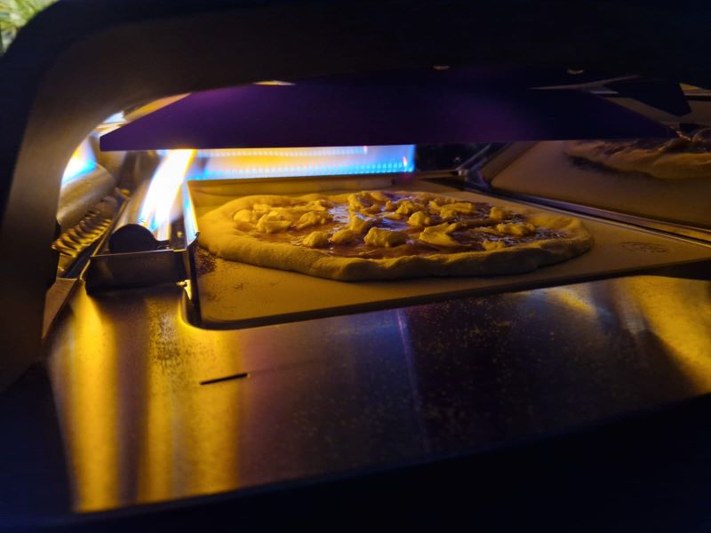 Pizza im Tony Gas-Pizzaofen während des Backvorgangs, umgeben von gleichmäßiger Hitze und intensivem Flammenbild.